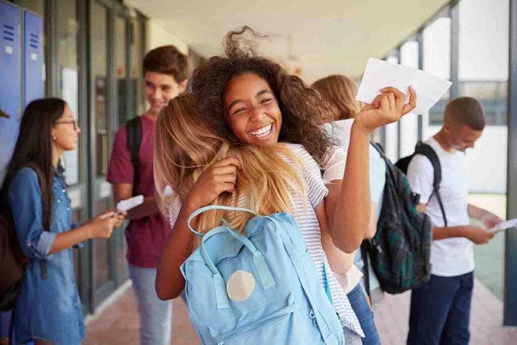 "Two cheerful girls celebrating the start of the new school year by lockers at school."