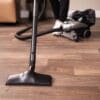 Kirby vacuum in canister mode, black and silver, on wooden floor.